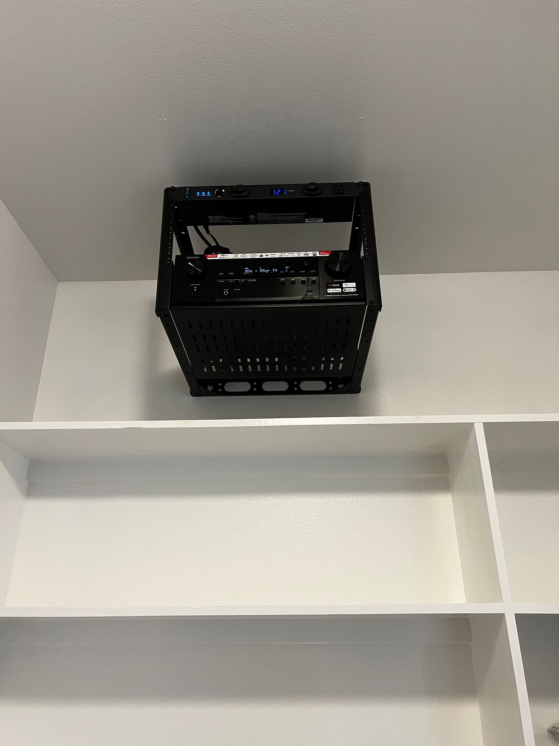 A black basket is sitting on top of a white shelf
