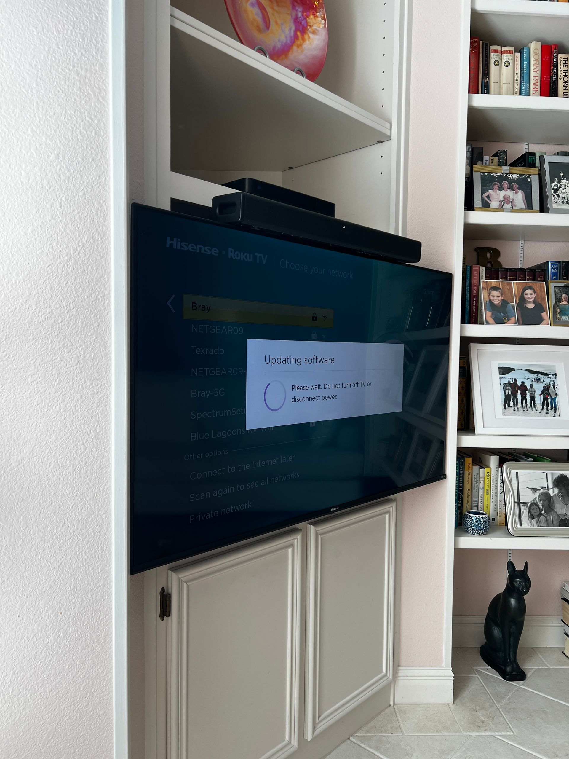 A black cat is sitting in front of a television in a living room