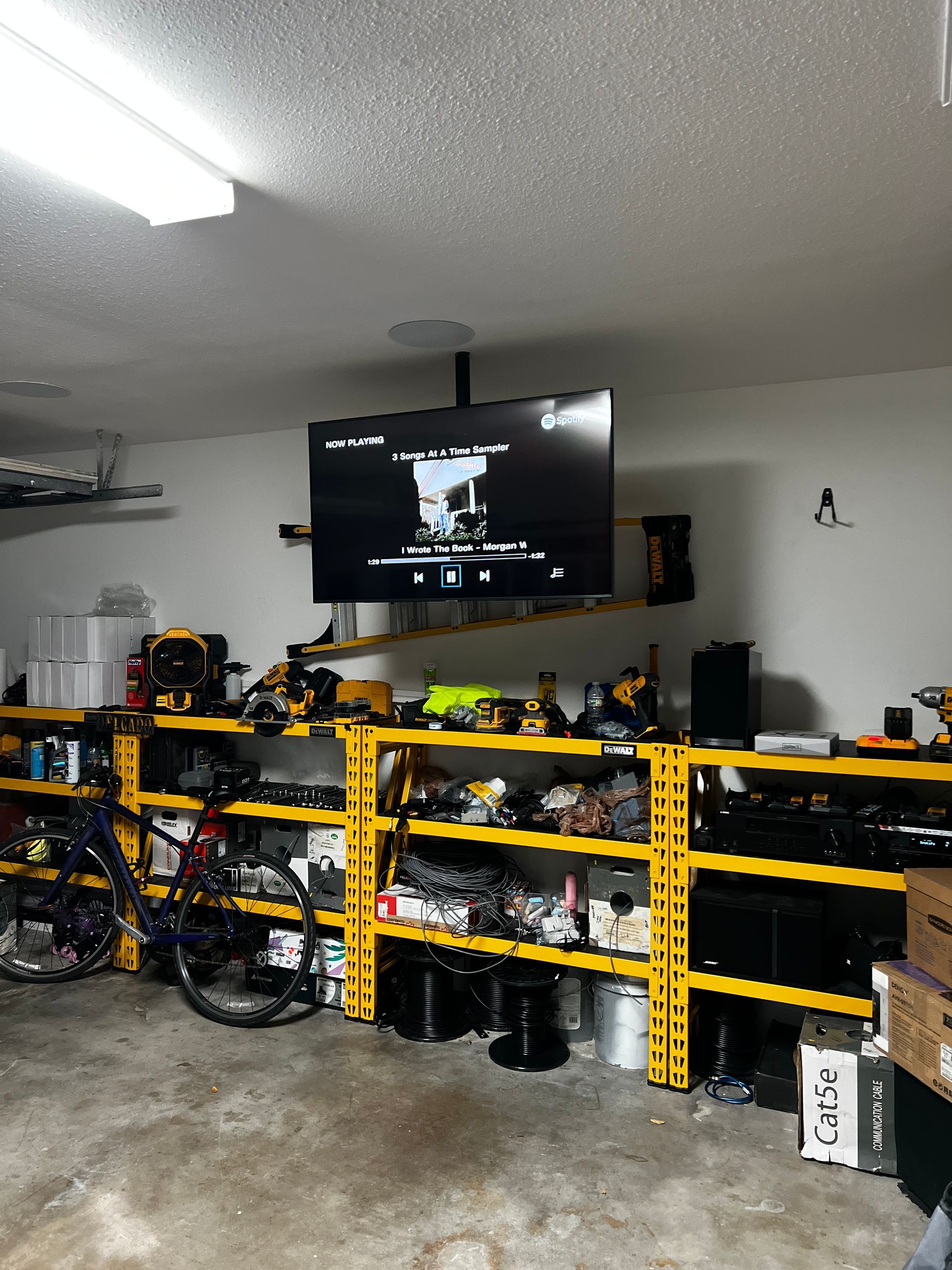A large flat screen tv is hanging from the ceiling in a garage