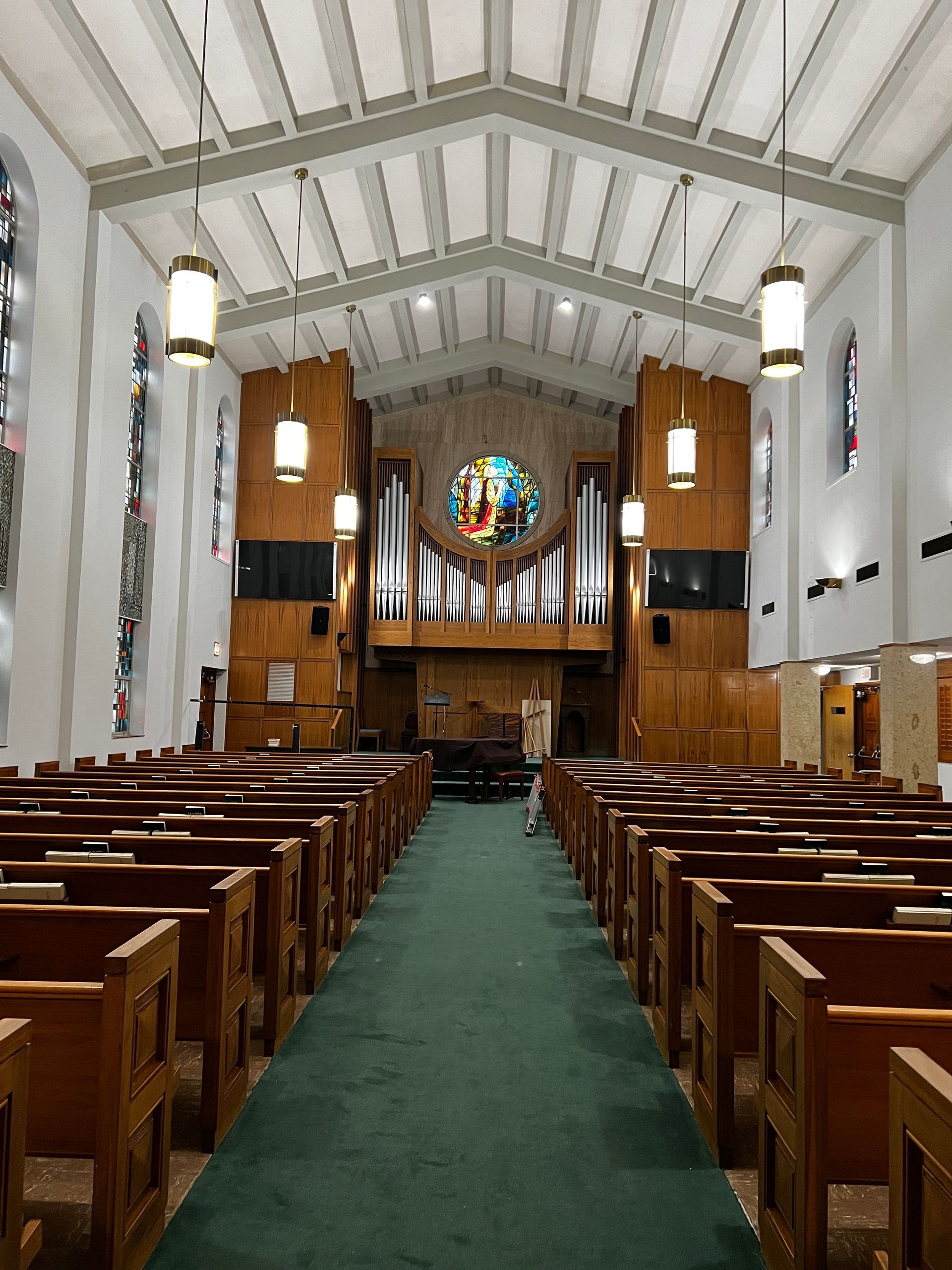 A church with rows of wooden pews and a stained glass window
