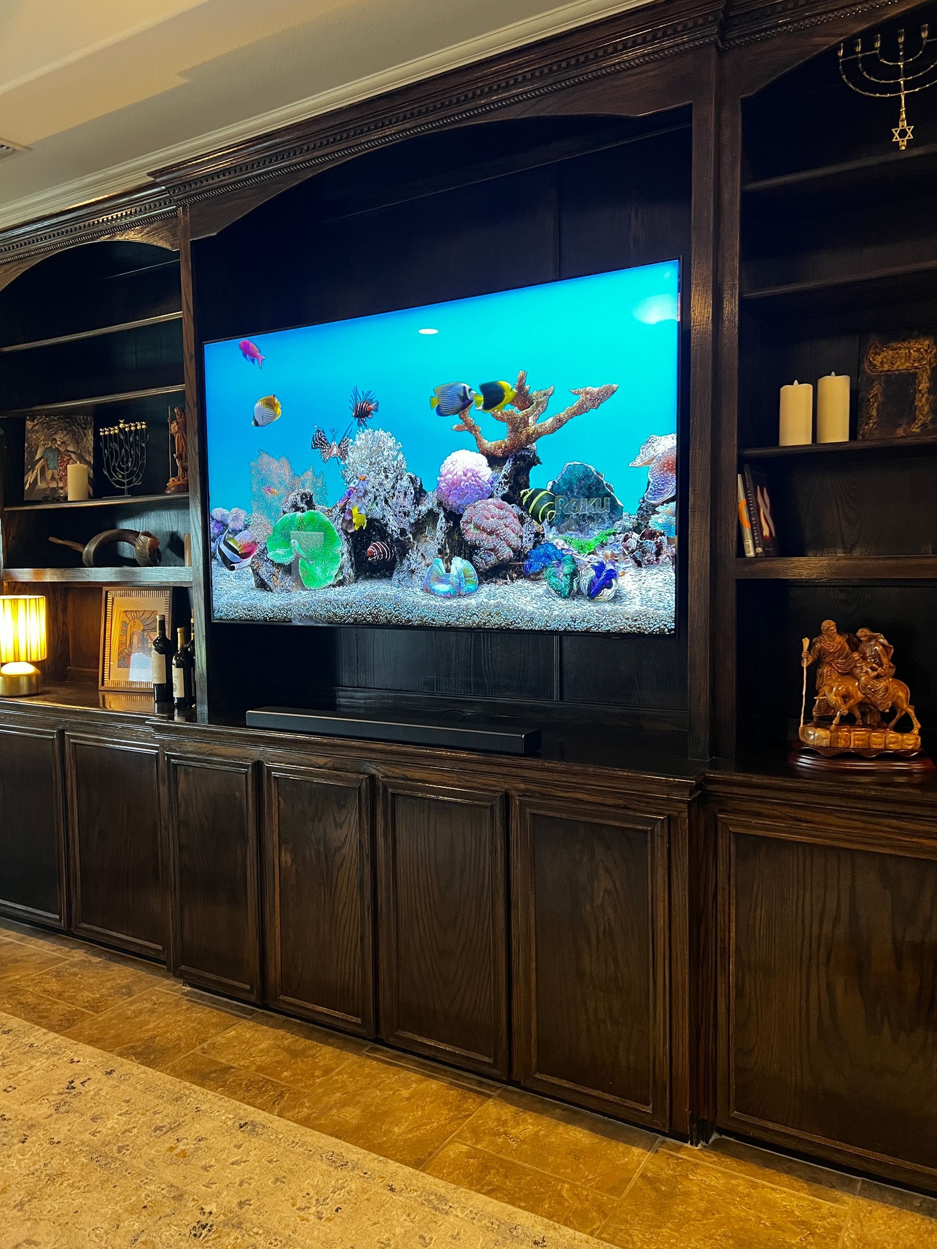 A large aquarium is sitting on top of a wooden entertainment center.