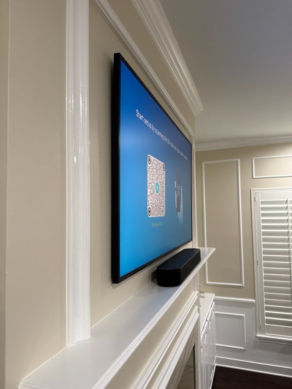 Wall-mounted TV with a blue screen above a shelf in a bright, white hallway