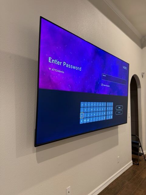A flat screen tv is mounted on a wall above a dresser.
