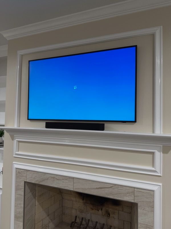 Flat-screen TV with a blue screen mounted above a white fireplace mantel in a living room