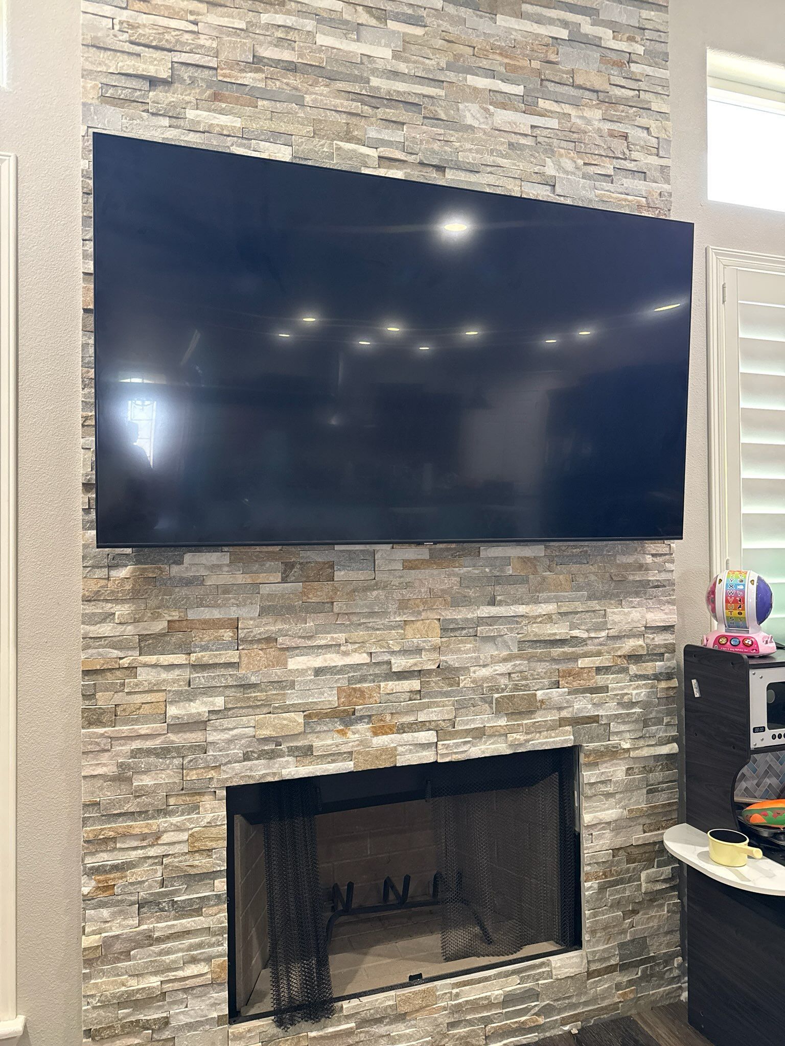Wall-mounted TV above a stone fireplace in a living room