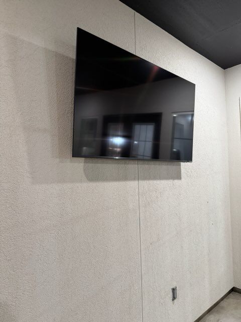 Wall-mounted flat-screen TV on a light textured wall in a modern interior room