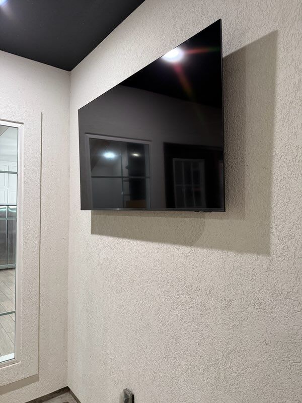 Wall-mounted flat-screen TV on a textured beige wall in a modern room corner