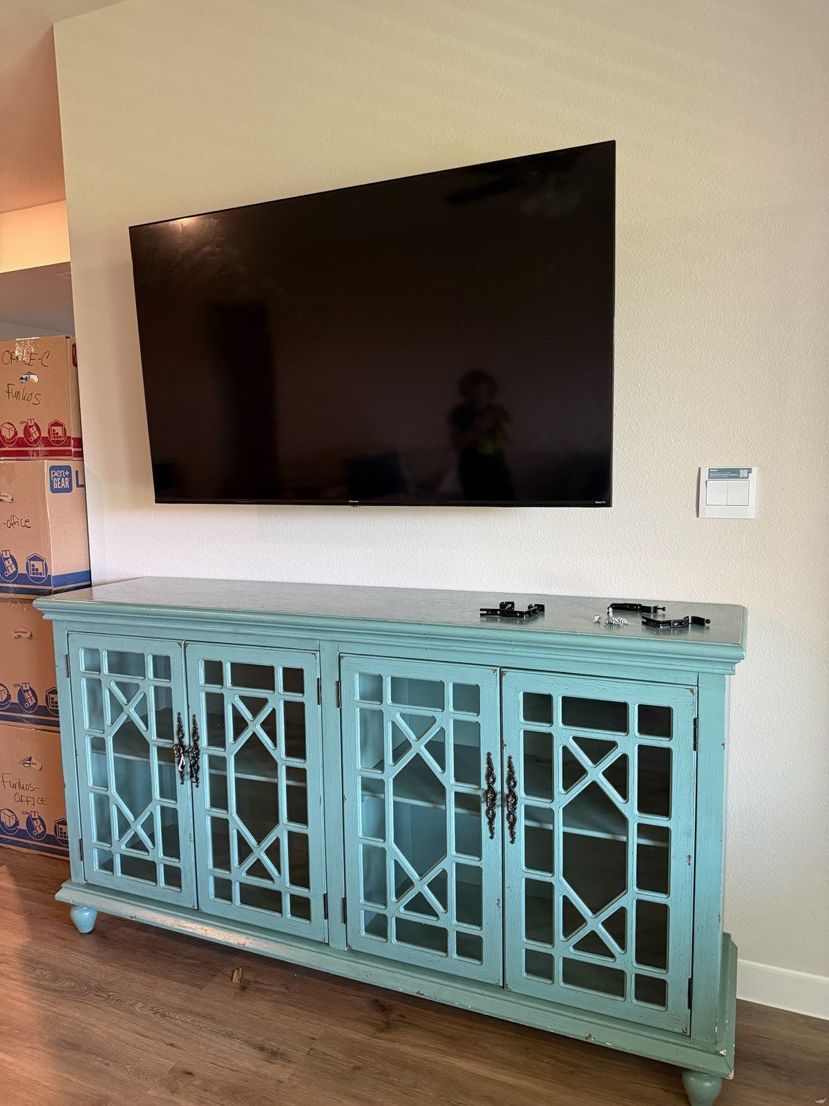 Wall-mounted TV above a turquoise patterned console cabinet in a living room