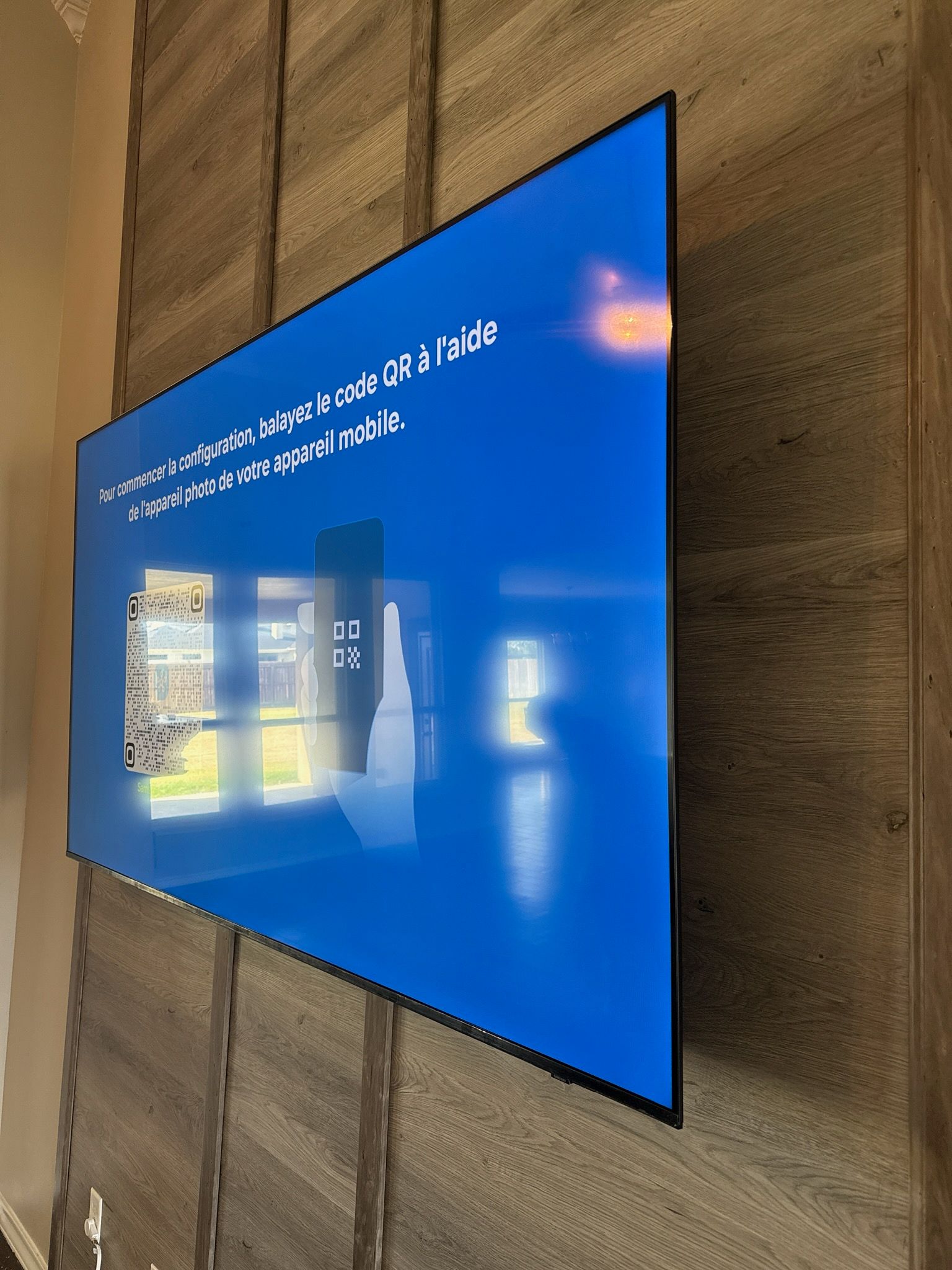 Wall-mounted blue digital display on a textured stone wall, showing a building image and white text.