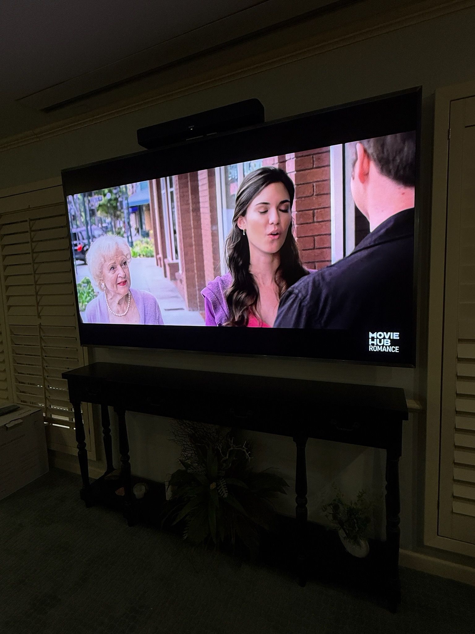 TV showing a woman talking to a man in a brick-lined street scene