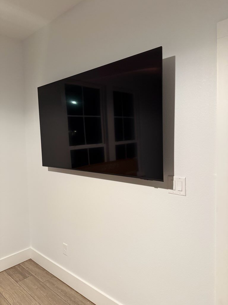 Wall-mounted flat-screen TV in a white room above a light wood floor