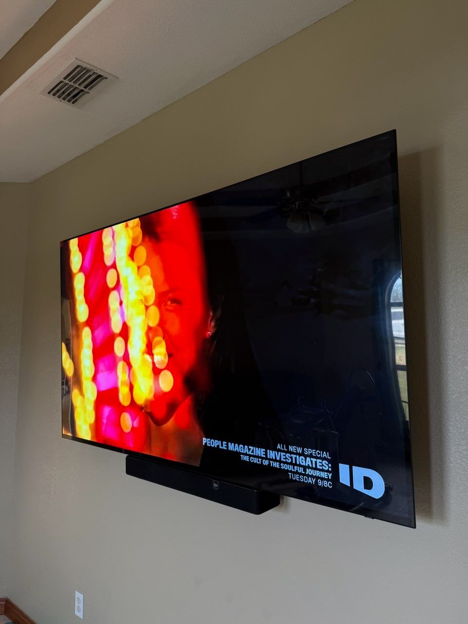 Wall-mounted TV displaying a red abstract scene with a small white logo in the lower right