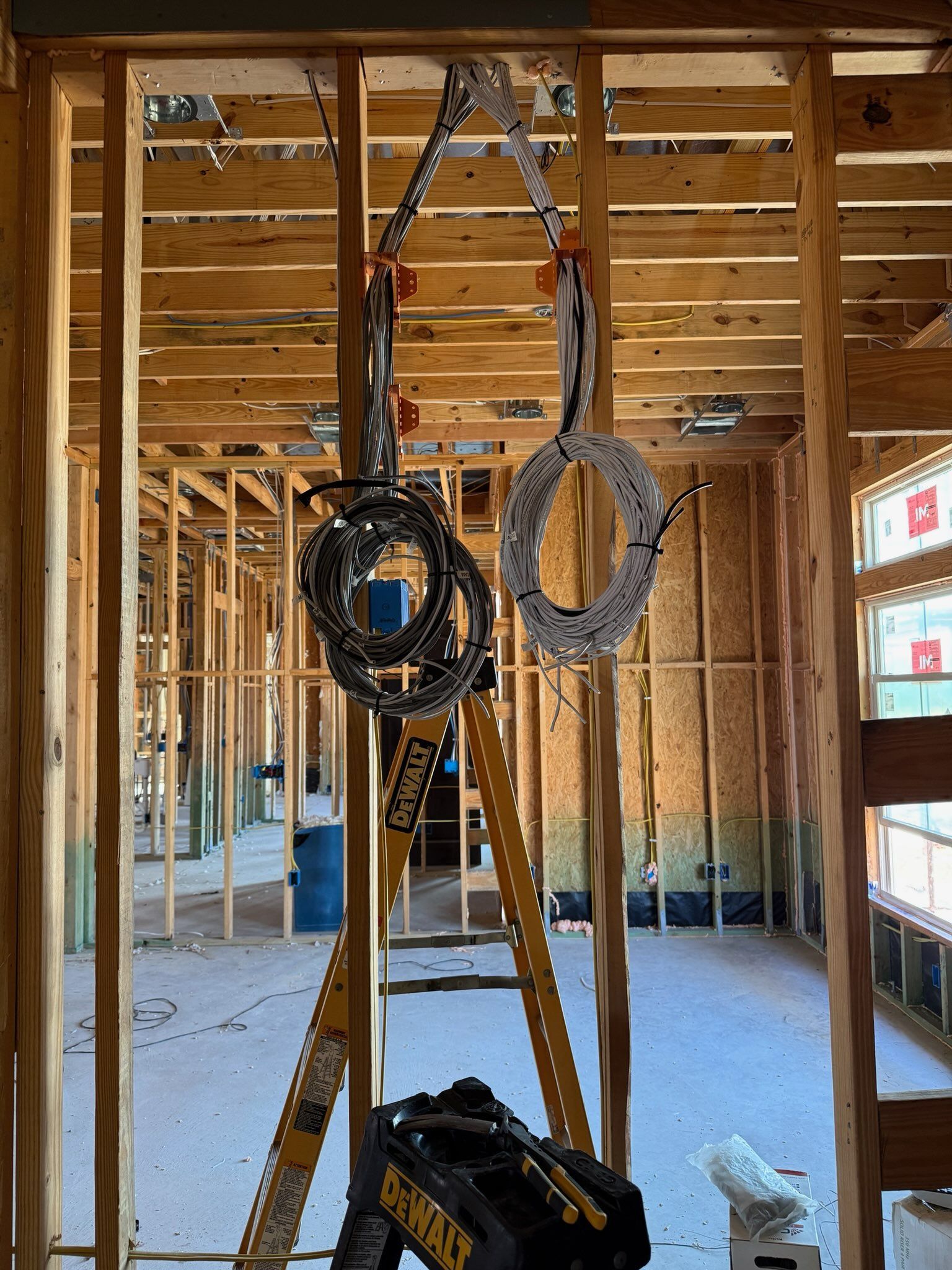 Construction interior with exposed wooden framing, ladder, and hanging tools in an unfinished room