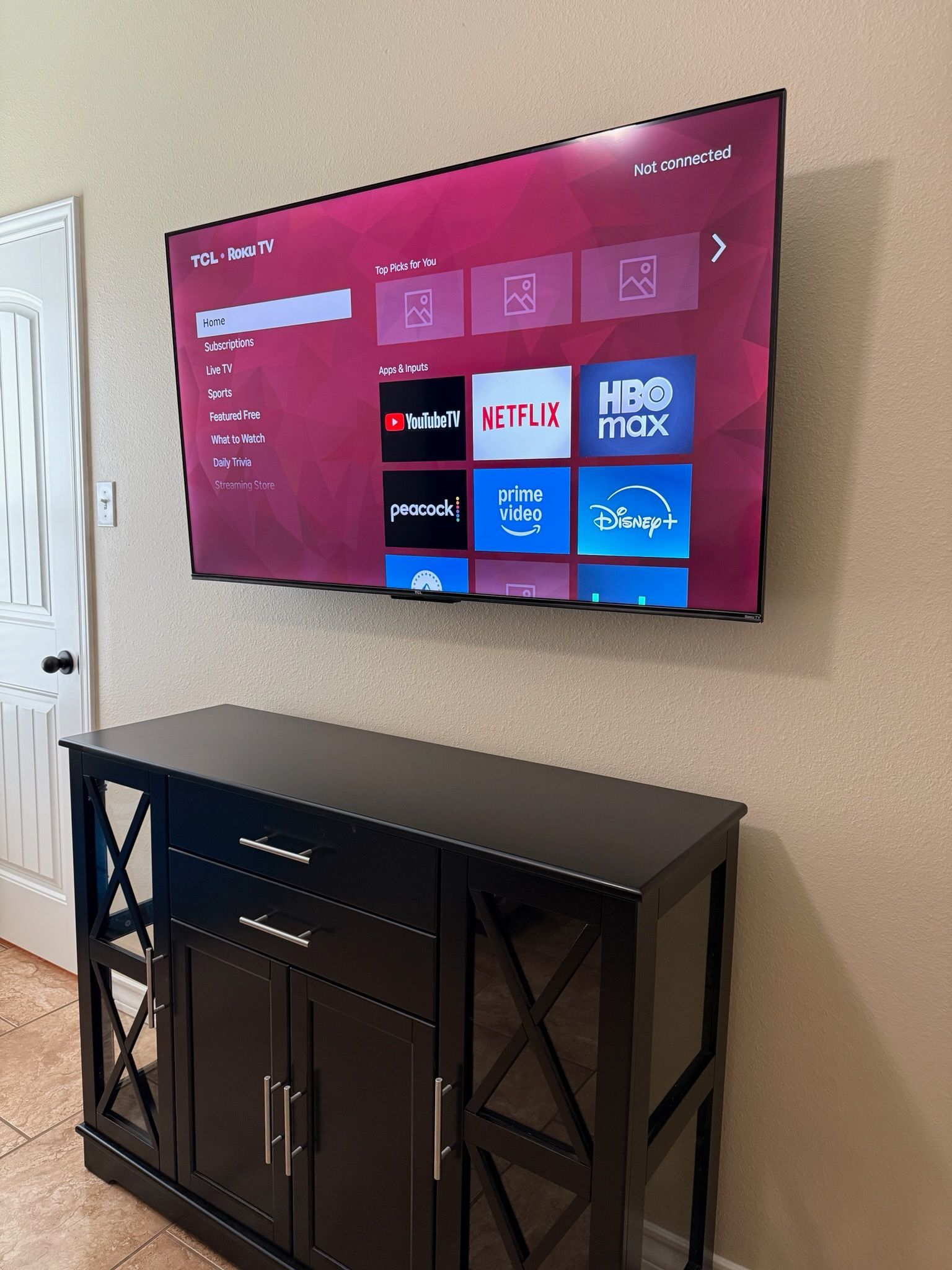 Wall-mounted TV streaming apps above a black console table in a beige living room