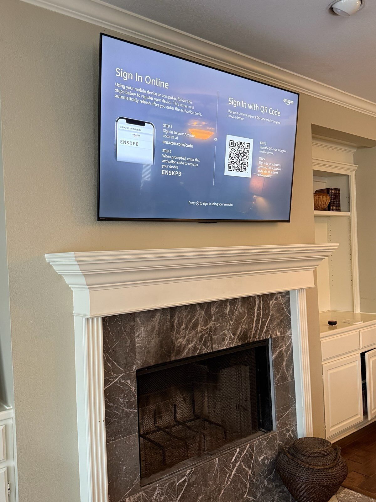Television mounted above a fireplace, displaying a sign-in screen, in a living room setting.