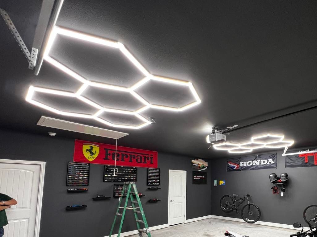 Garage with hexagon-shaped LED lights on the ceiling; Ferrari banner, bikes, and tools on the walls.