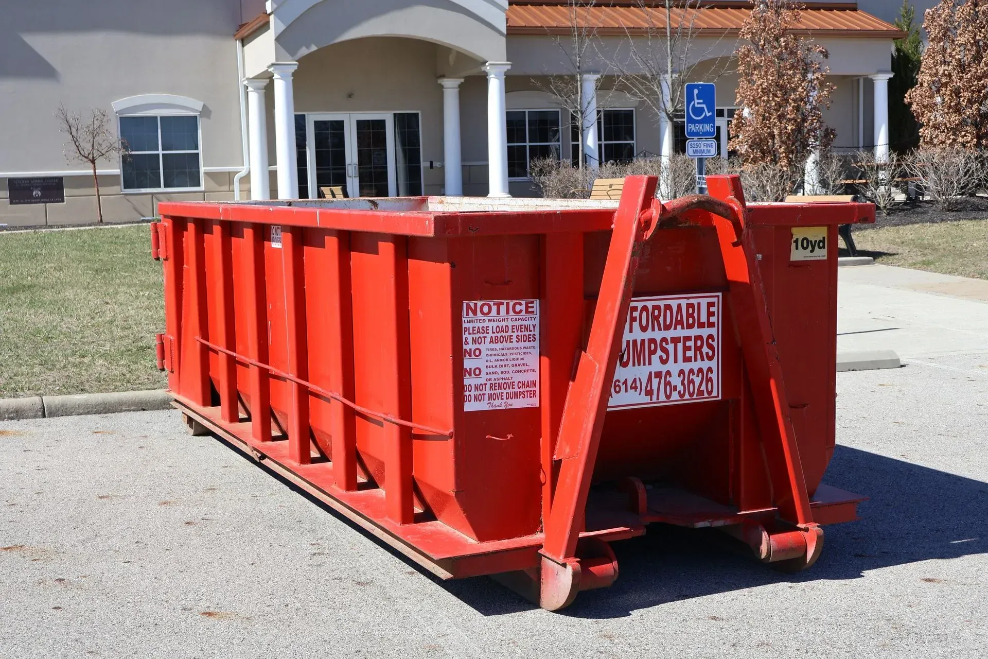 Red 10-yard roll-off dumpster for residential dumpster rental on pavement