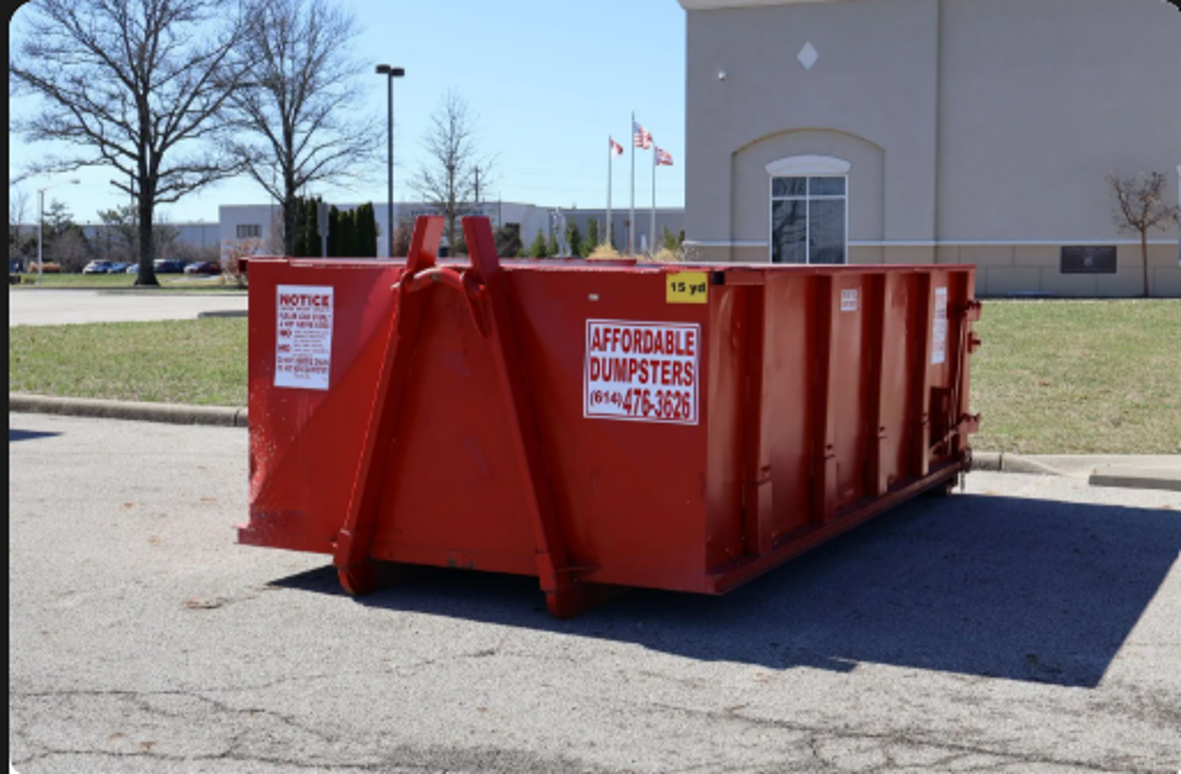 Red commercial waste dumpster rental container placed in a parking lot.