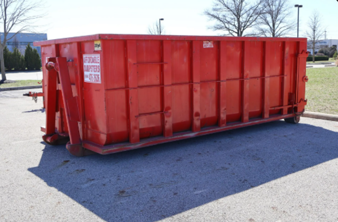 Red roll-off home cleanout dumpster rental container parked outdoors.