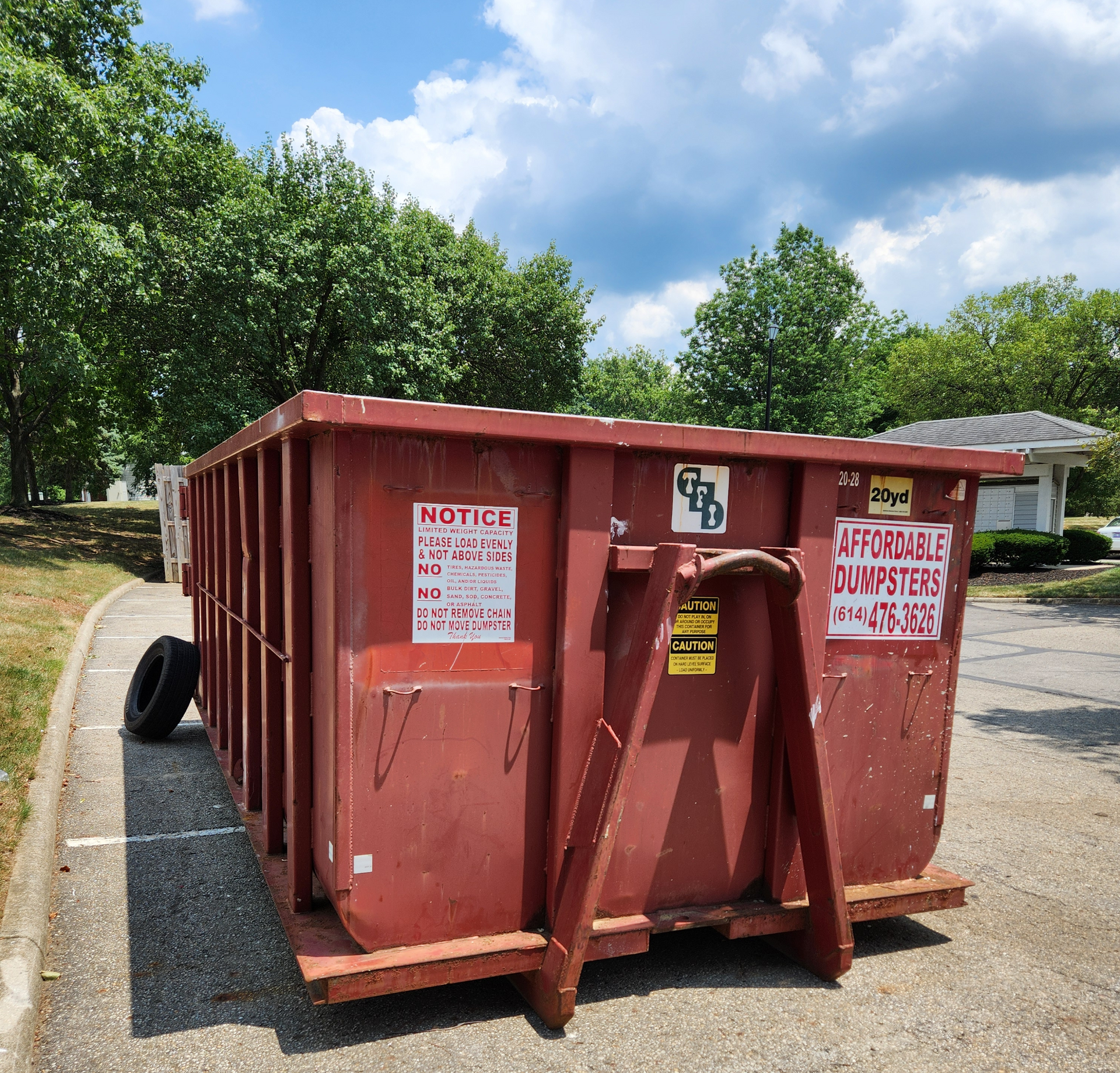 A waste bin filled with chairs and sofas | Gahanna, OH - Affordable Dumpsters A large red dumpster with signage | Gahanna, OH - Affordable Dumpsters