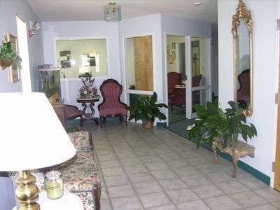 Living room with tile floor, red chairs, potted plants, and a large wall mirror