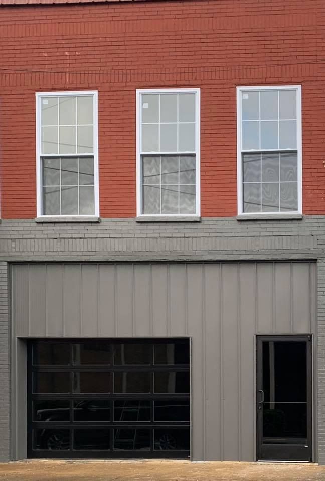 A red brick building with three windows and a garage door