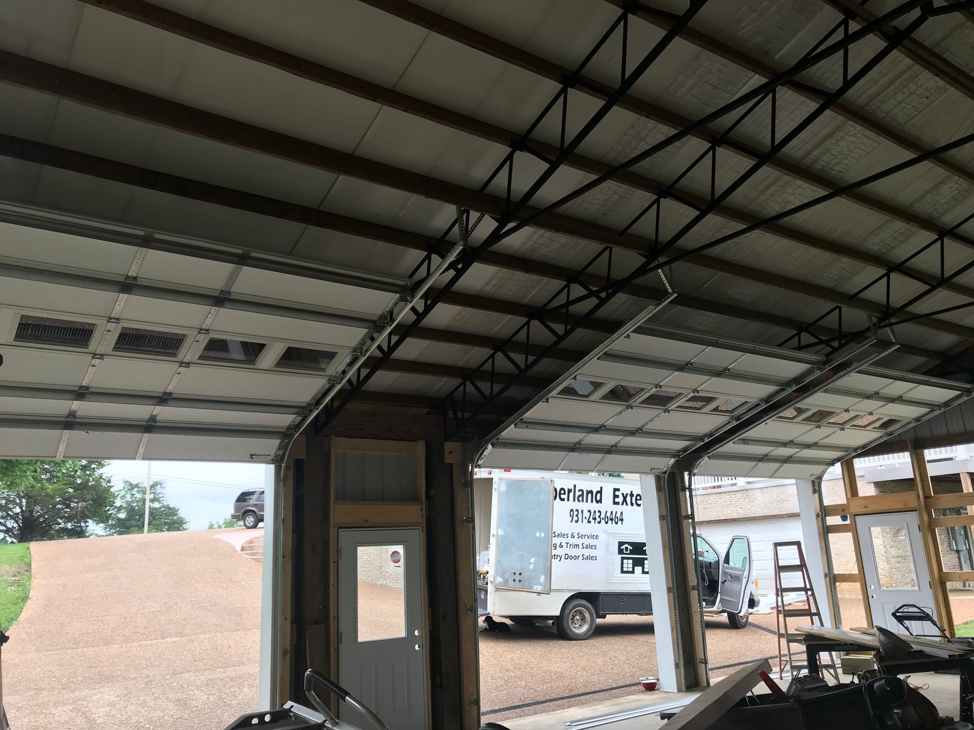 A white truck is parked in a garage with the door open.