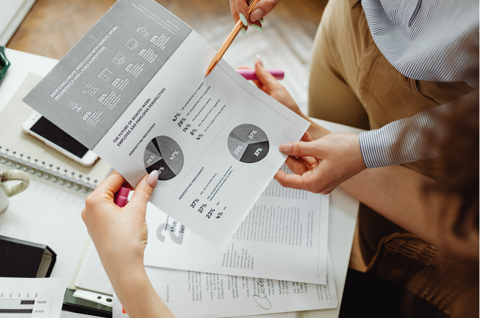Two people reviewing business data on paper documents, including charts and graphs.
