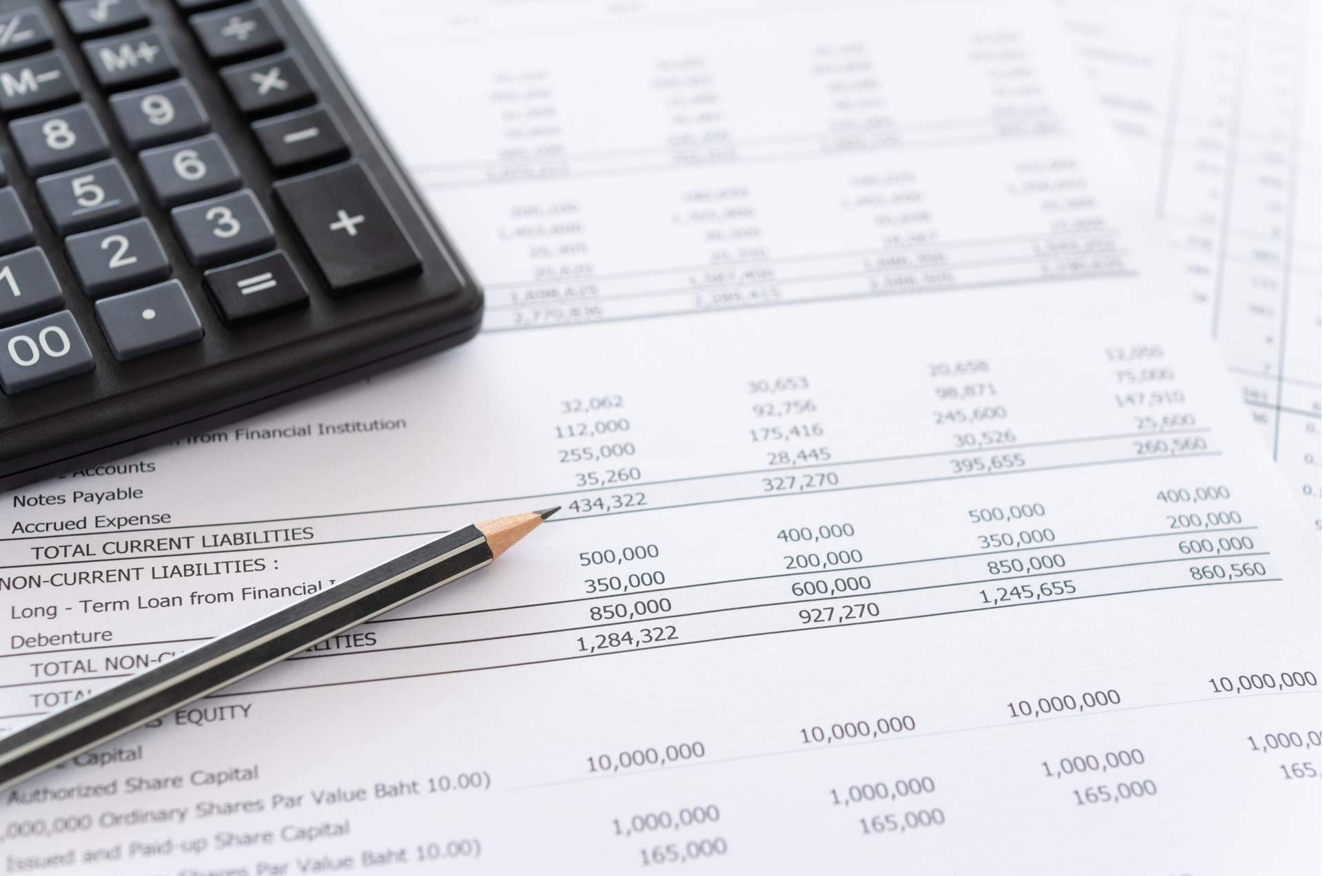 Calculator and pencil on a financial document with numbers and text.