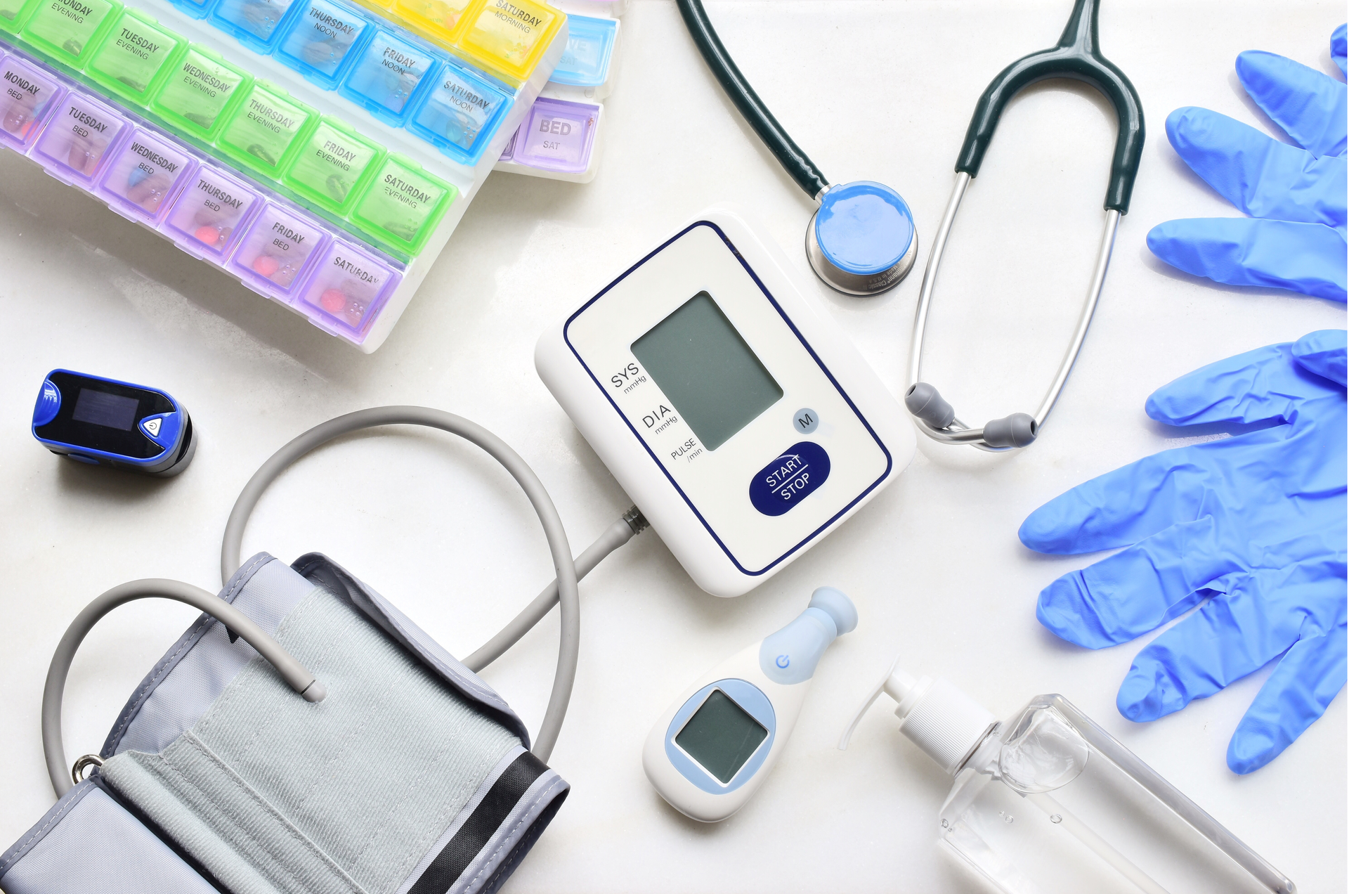 Medical supplies: pill organizer, stethoscope, blood pressure monitor, pulse oximeter, gloves, hand sanitizer.