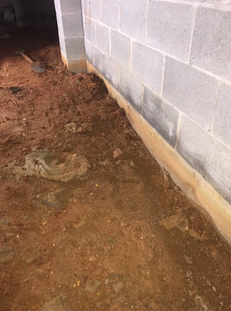 A brick wall with a lot of dirt around it.