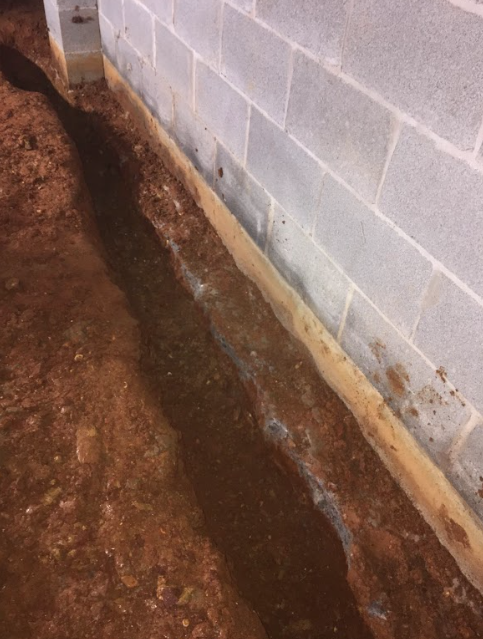 A brick wall with a trench in front of it