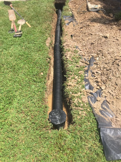 A drain pipe is being installed in a yard.