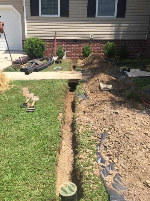 A drainage system is being installed in front of a house.