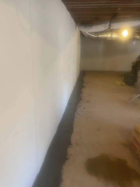 A basement with a white wall and a brown floor.