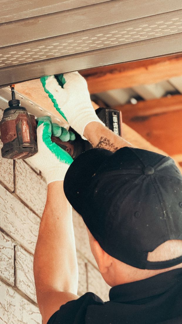 Person in gloves applying green sealant to a ceiling crack indoors, viewed from below