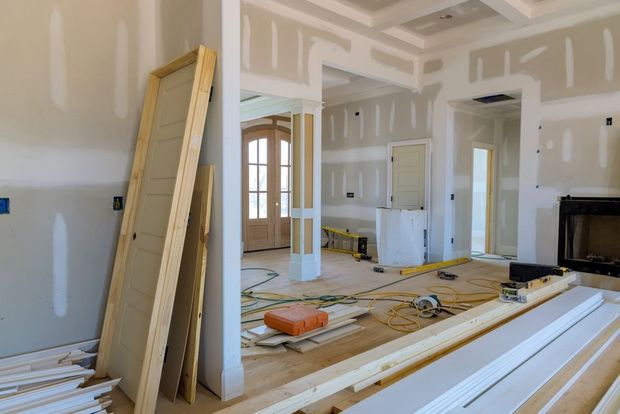 Interior of a home under renovation, with drywall, tools, and construction materials in an unfinished room.