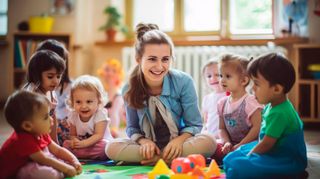 A woman is sitting on the floor with a group of children playing with toys.