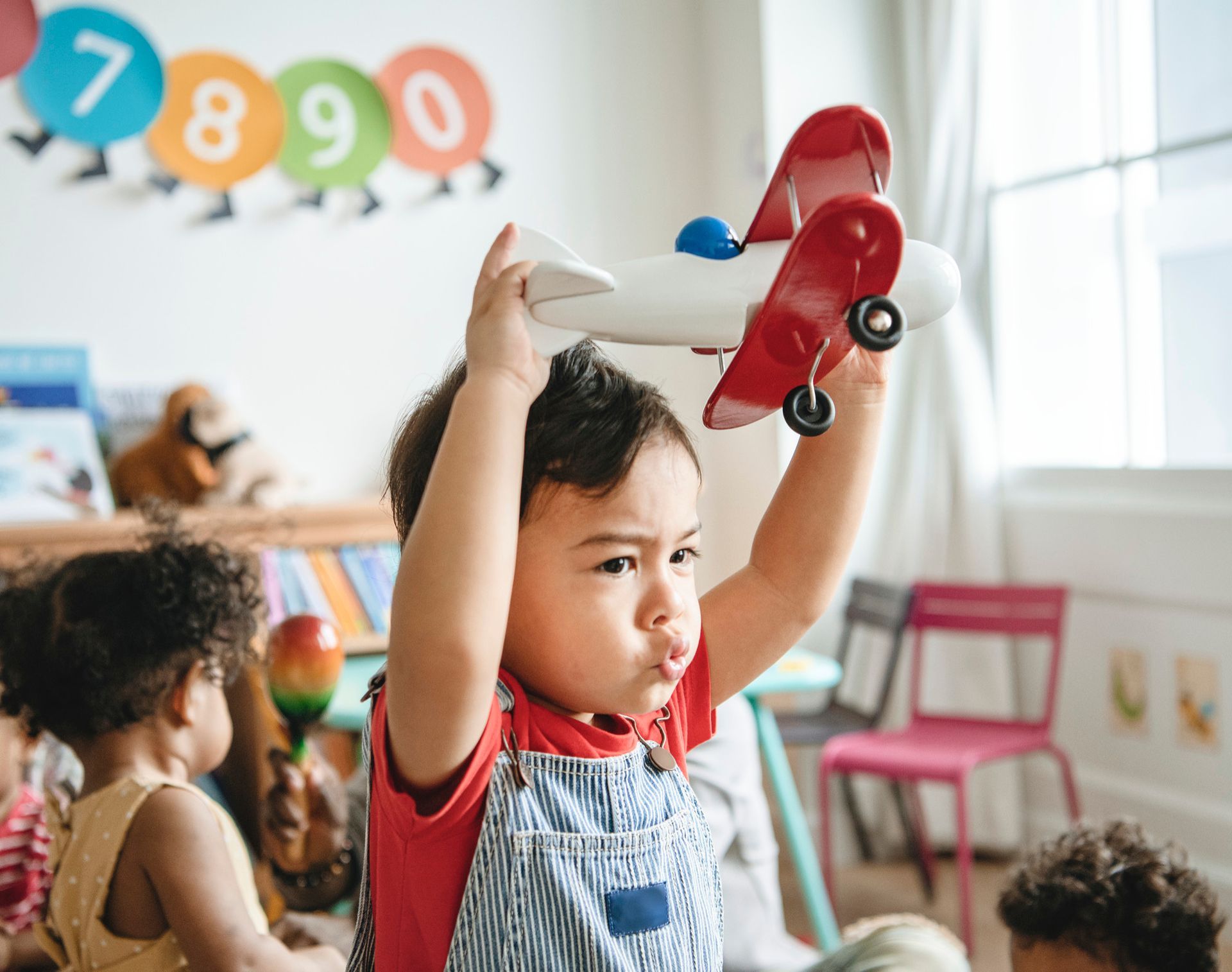 A young boy is holding a toy airplane over his head.