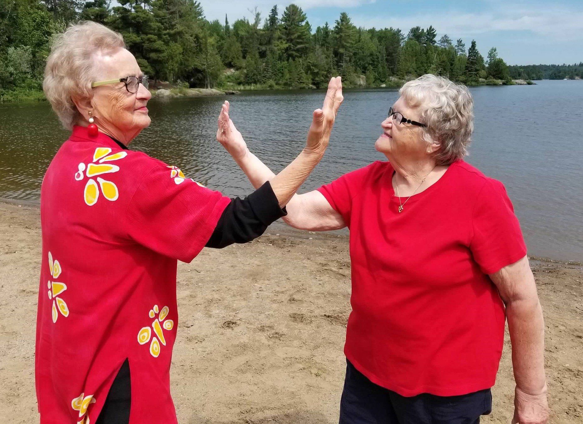 A photo of two older women in red shirts on the beach