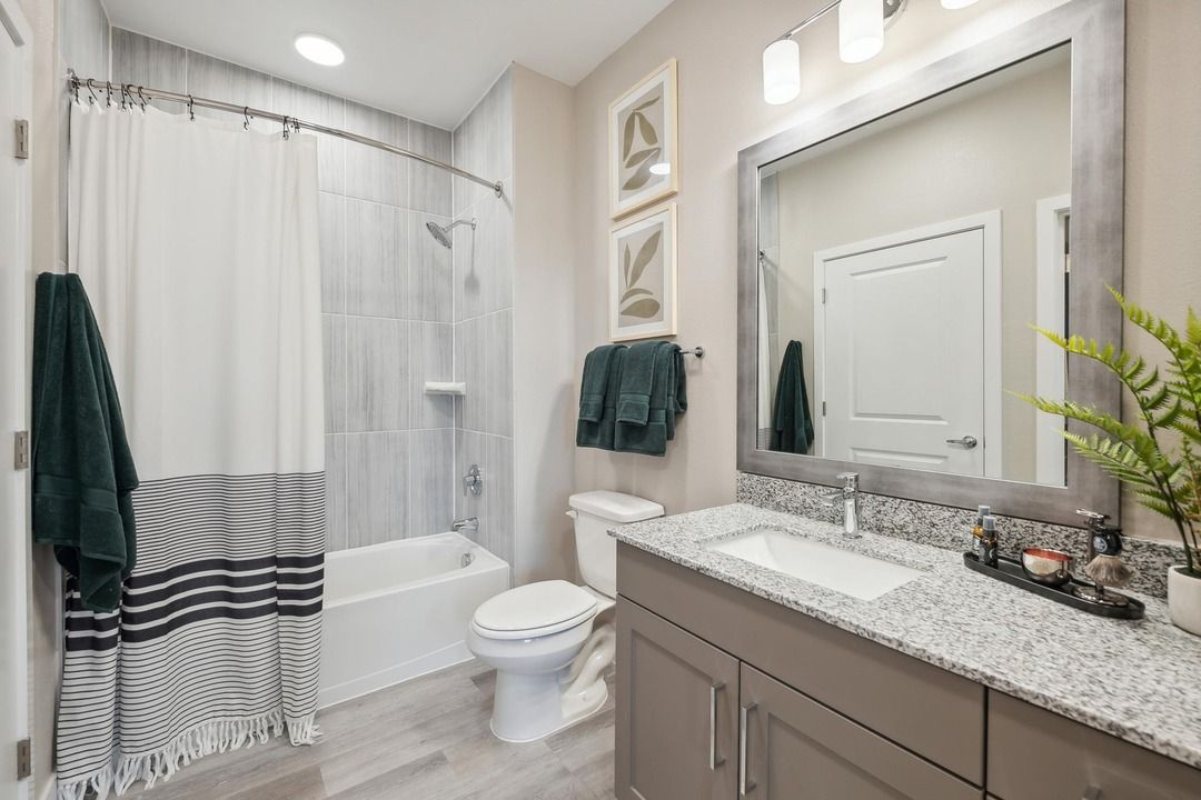 A bathroom with a sink , toilet , shower and mirror.