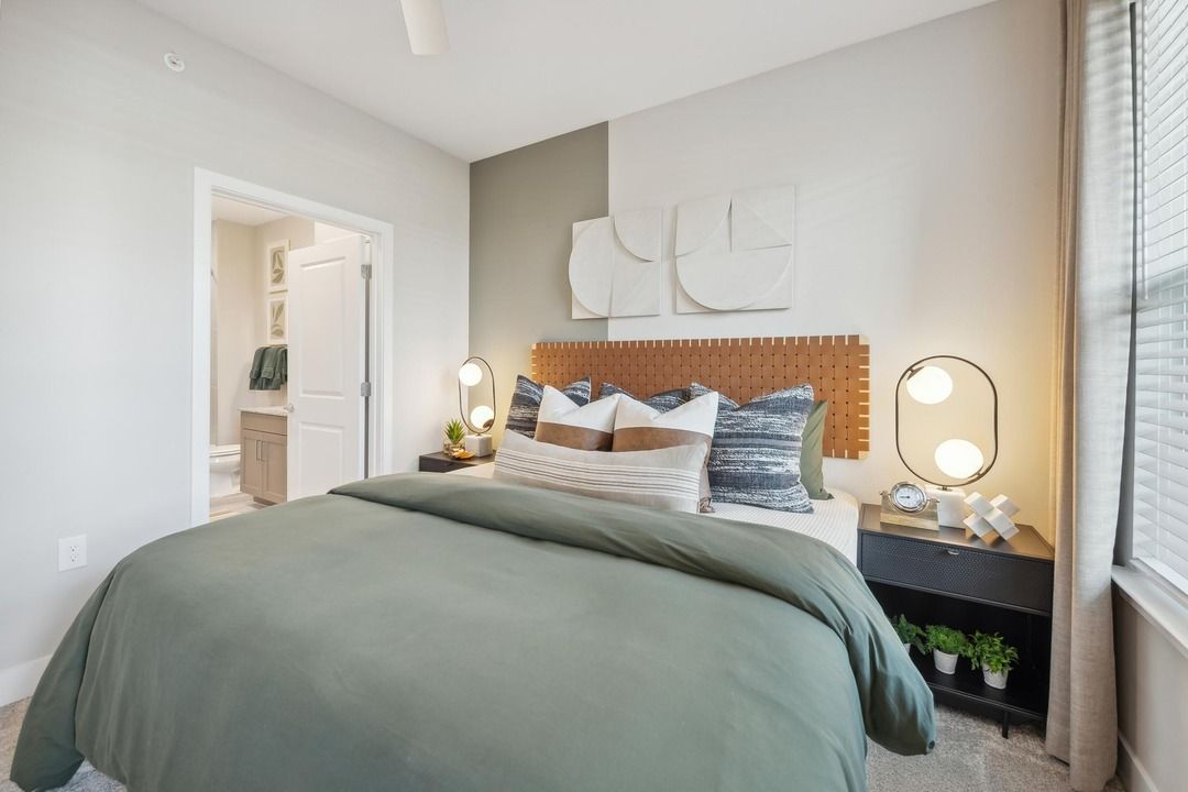 A bedroom with a bed , nightstand , lamps and a window.