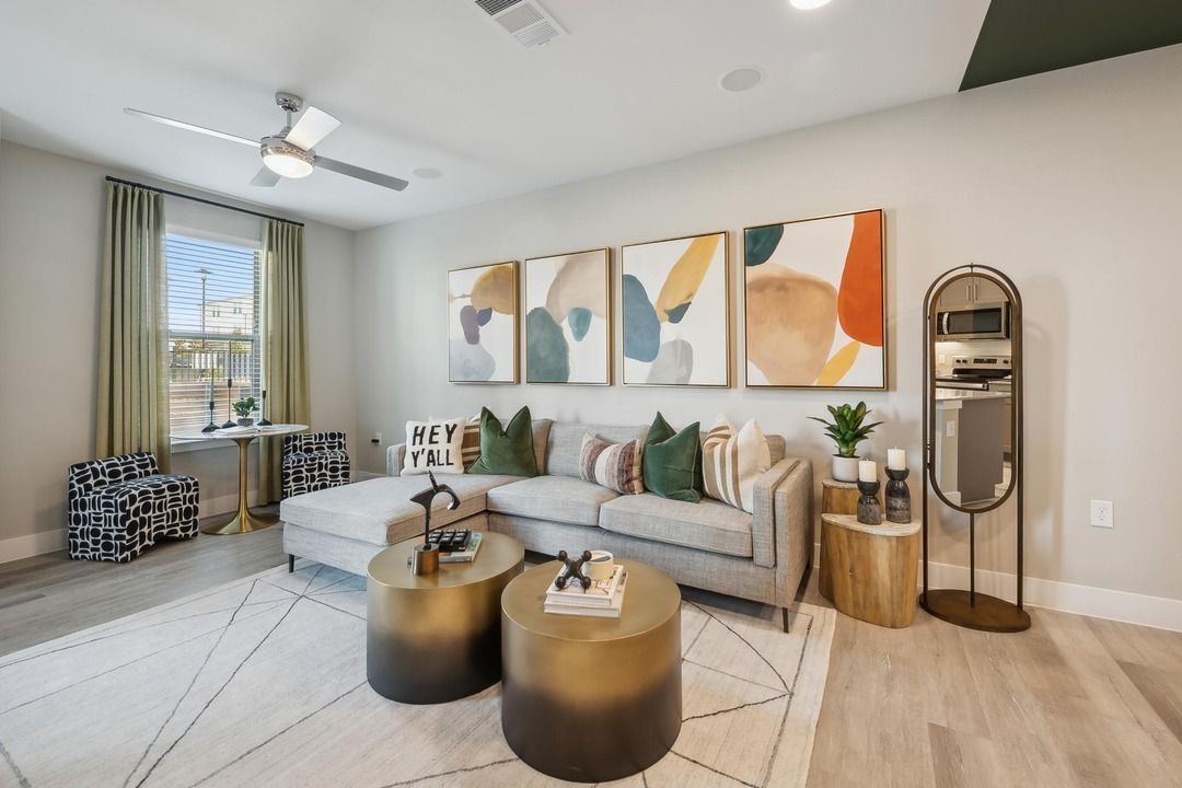 A living room with a couch , two coffee tables , a mirror and a ceiling fan.