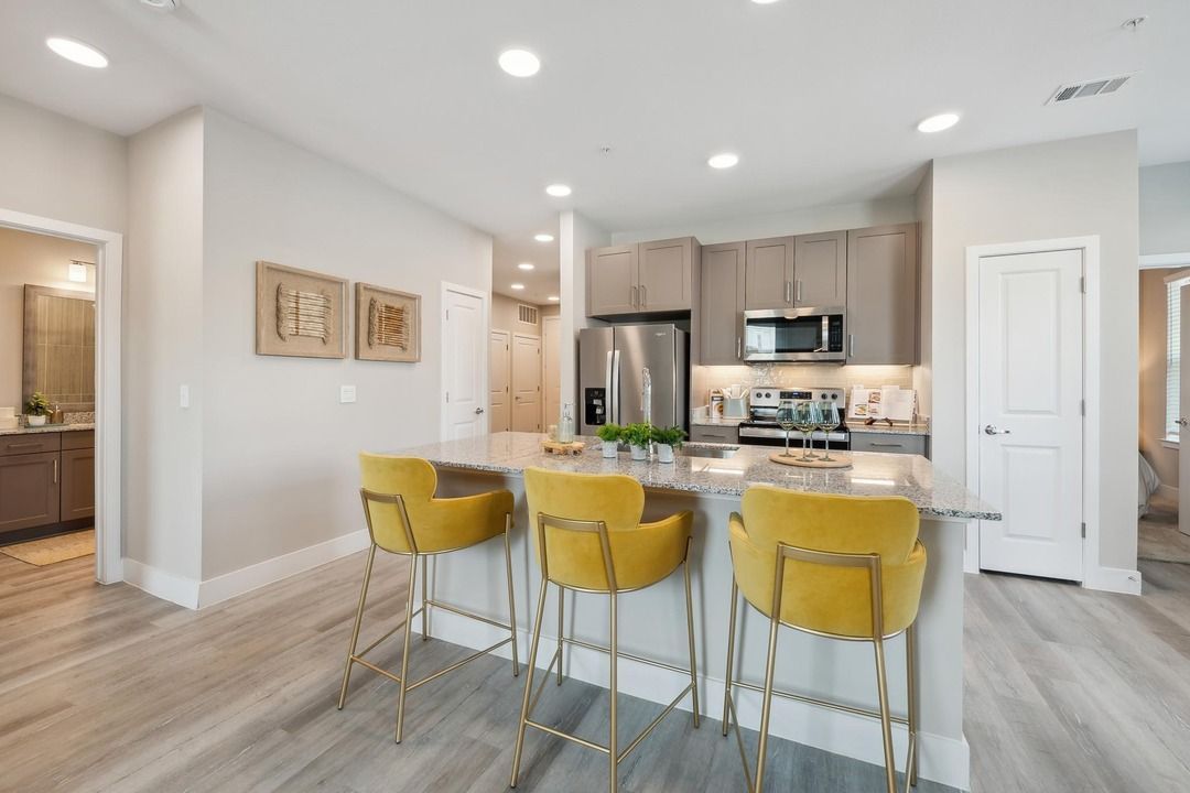 A kitchen with a large island and yellow bar stools.