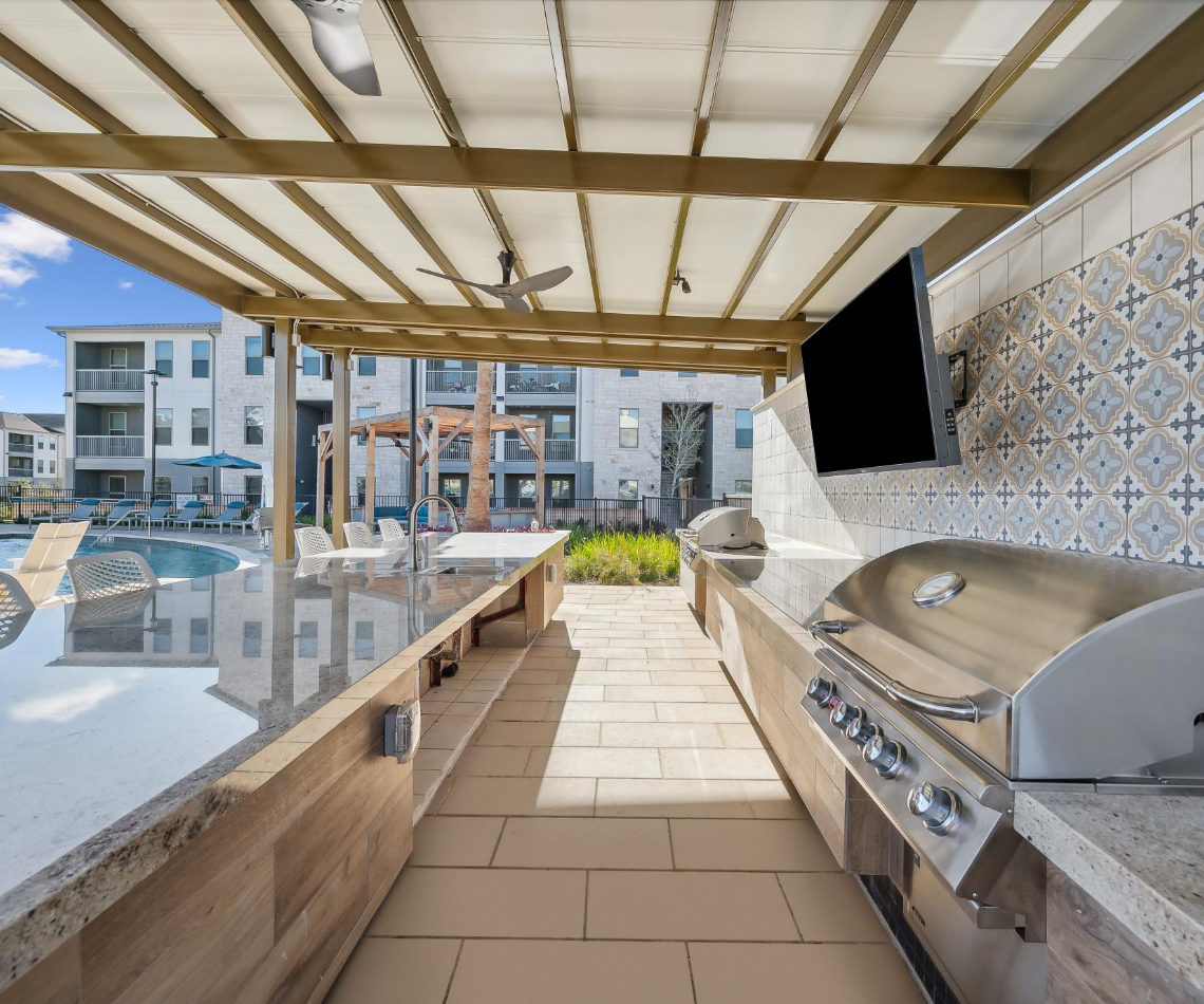 An outdoor kitchen with a grill and a television