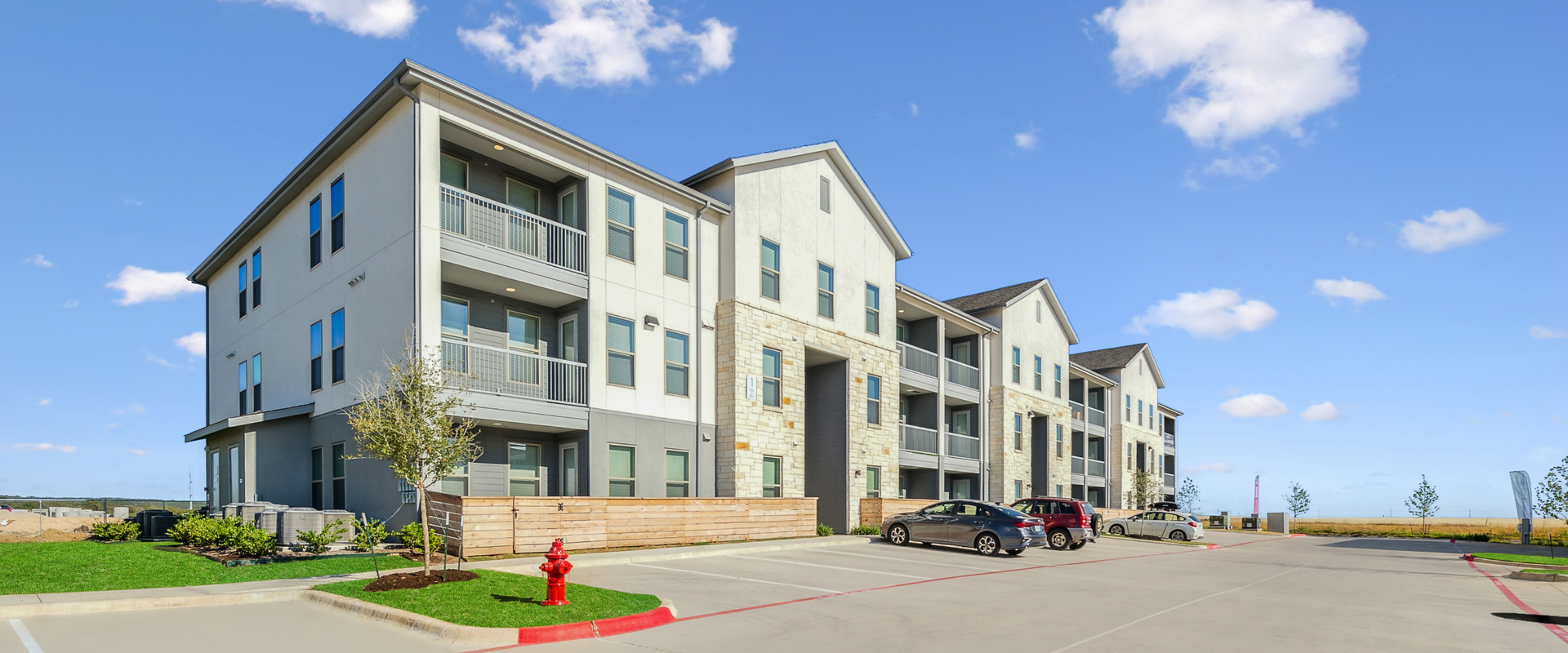 A large apartment building with cars parked in front of it.