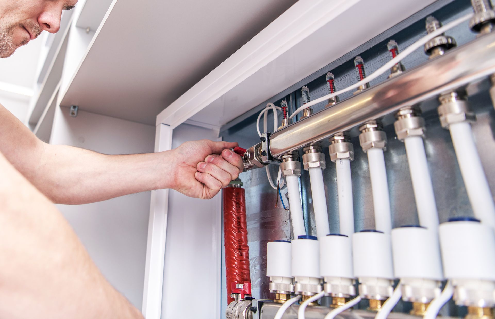 A partial view of a plumber repairing a water pipe system. A partial view of a plumber repairing a water pipe system.