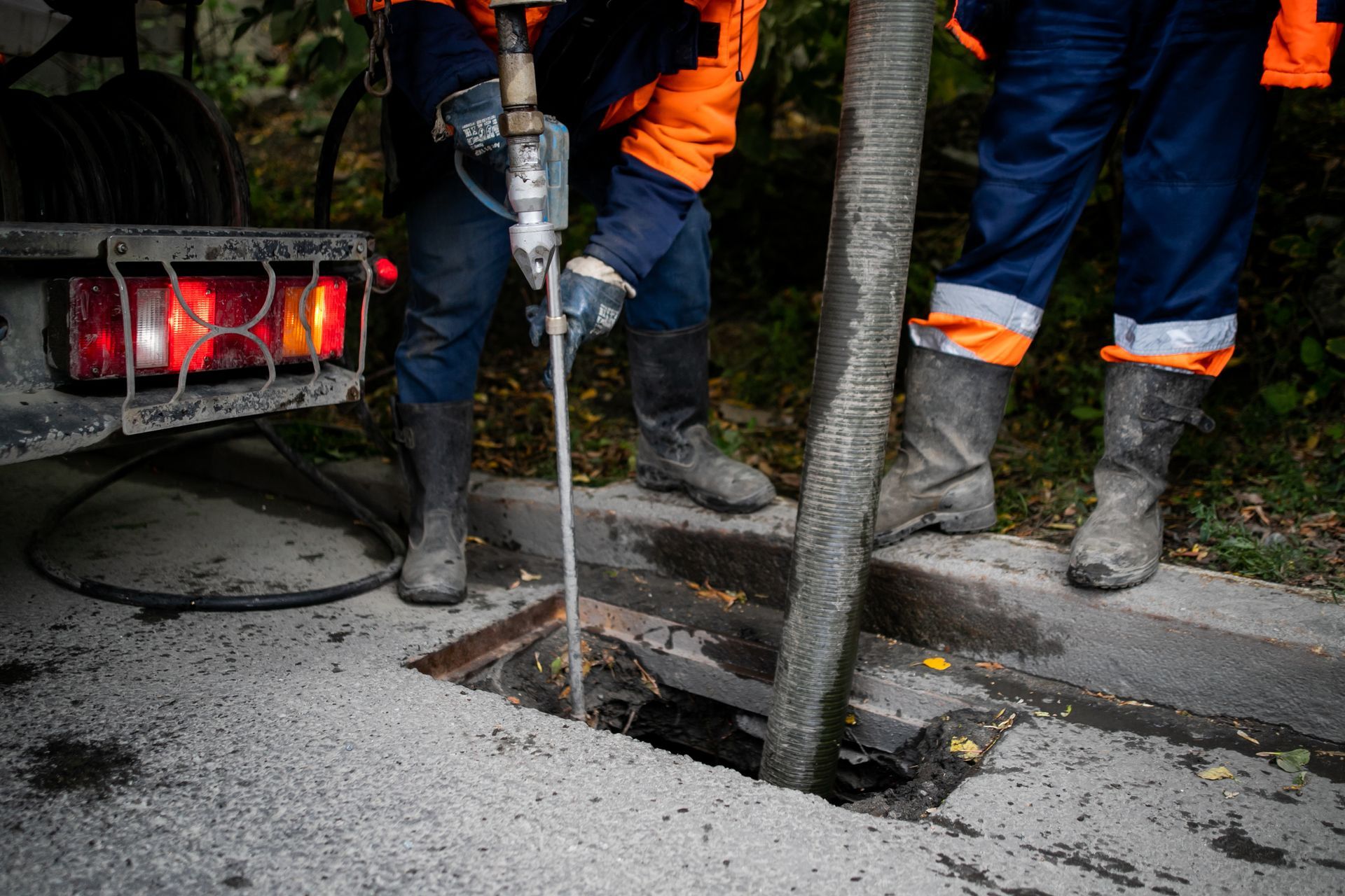 Two professionals cleaning a storm drain with a pump and water. Two professionals cleaning a storm drain with a pump and water.
