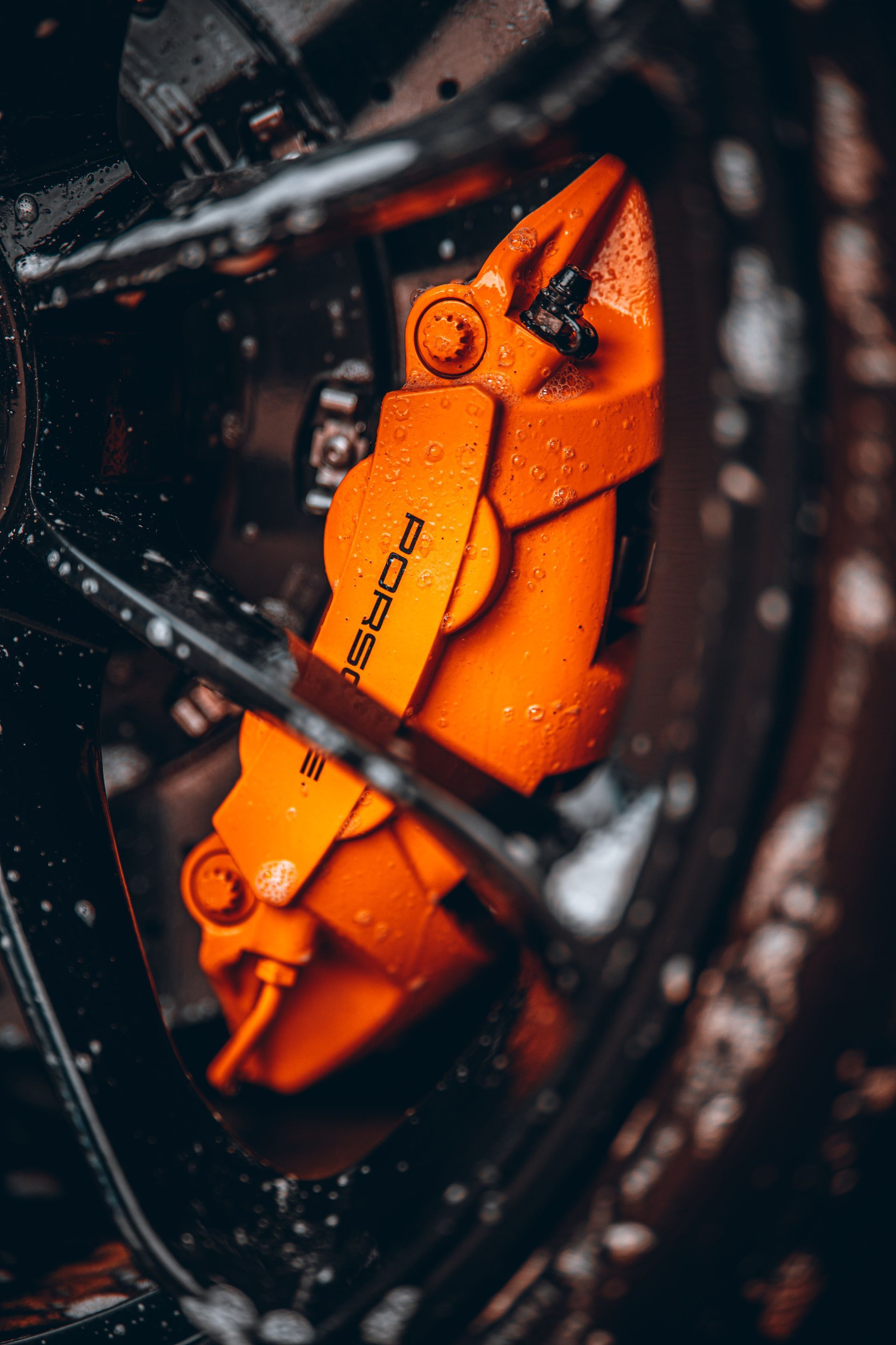 A close up of an orange brake caliper on a car wheel.