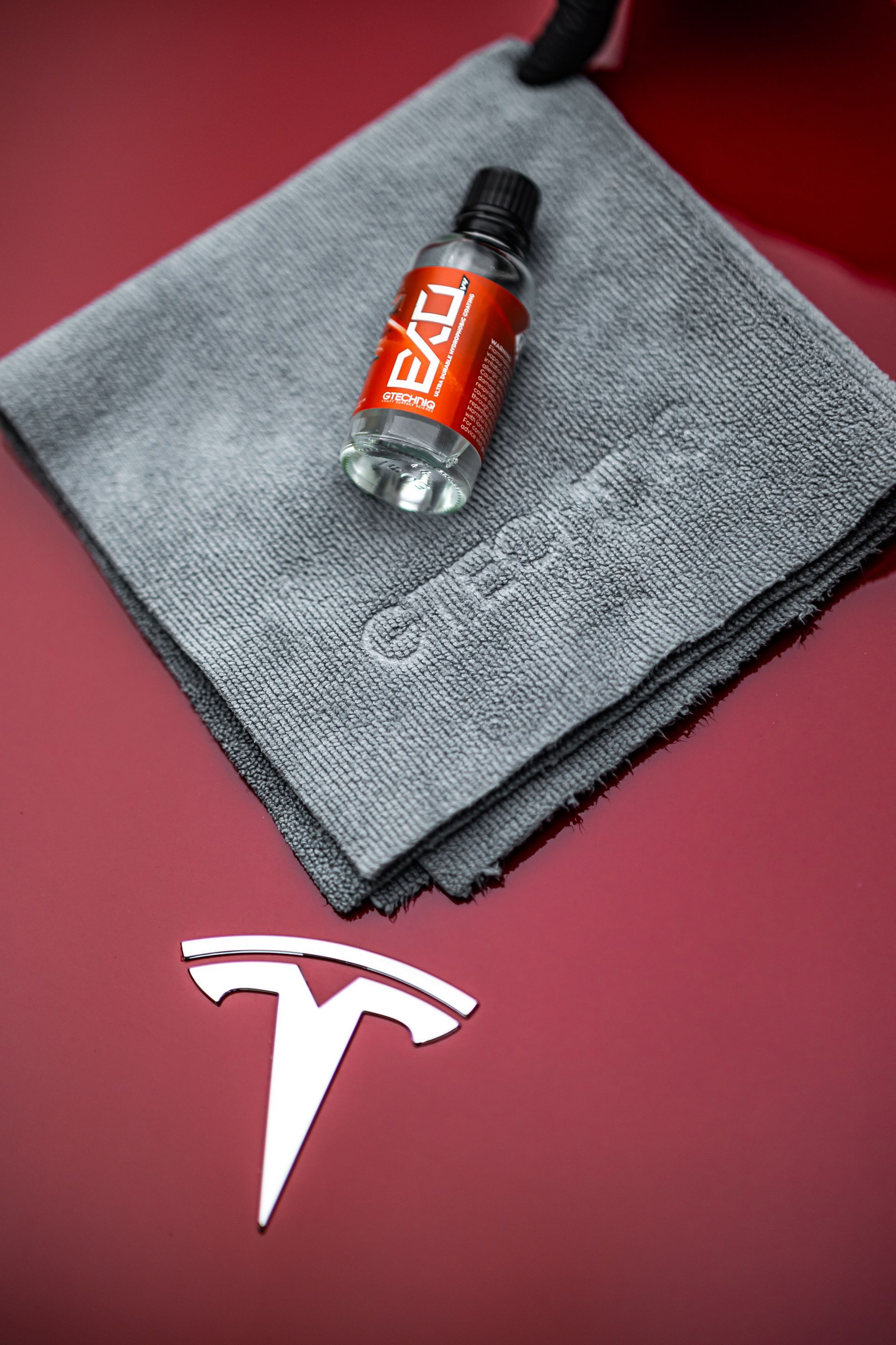 A bottle of liquid is sitting on top of a towel next to a tesla logo.